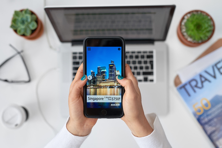 Modern mobile lifestyle making travel bookings online on smartphone  cellphone app, attractive holiday destinations vacationの写真素材