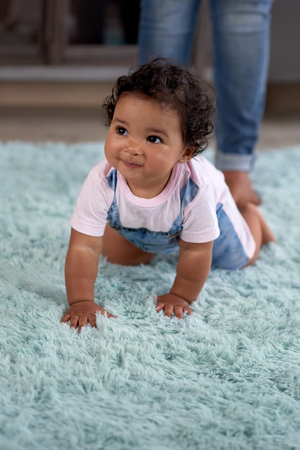 Baby girl crawling around on carpet, learning how to move walk babyhood development movementの写真素材
