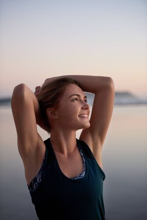 Carefree woman looking up and smiling after workoutの写真素材
