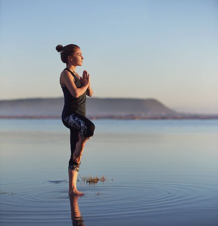 Woman blancing in yoga pose at the beach for a healthy lifestyleの写真素材