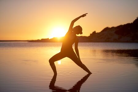Yoga stretch woman silhouette at the beach healthy welness conceptの写真素材