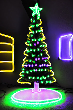 Dark christmas tree illuminated with neon lights on dark background, wallpaper christmas banner Ai Generatedの素材