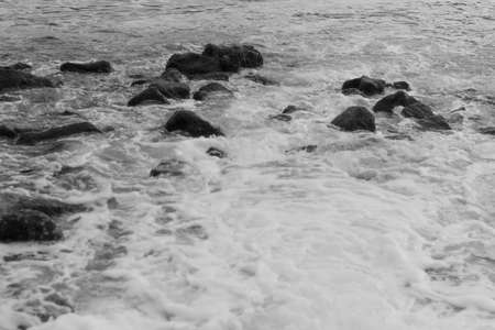 water come in to the sea across the stones. black and white shot.の写真素材