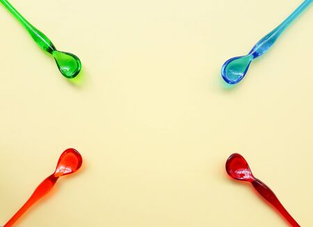 Four color plastic spoons on yellow paper backgroundの写真素材