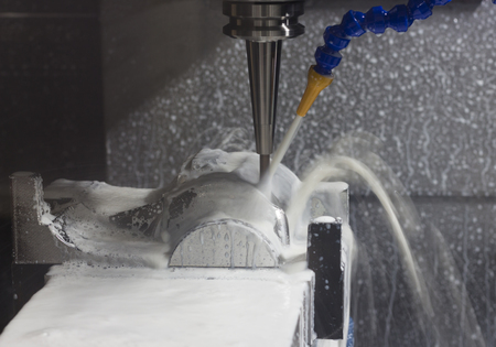 CNC machining Center is cutting part with white coolant ; selective focusの写真素材
