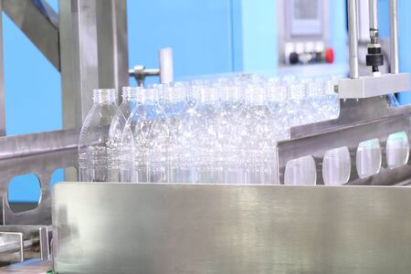 a group of platic bottles in production line wait to fill water . engineering equipment indutrial...