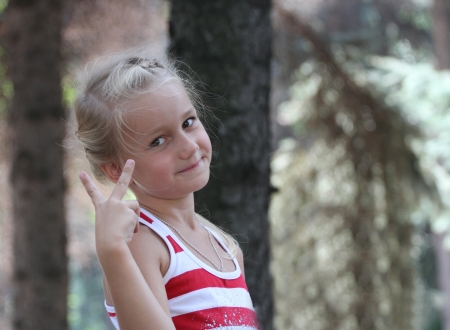 small joyful girl shows fingers a victoryの写真素材