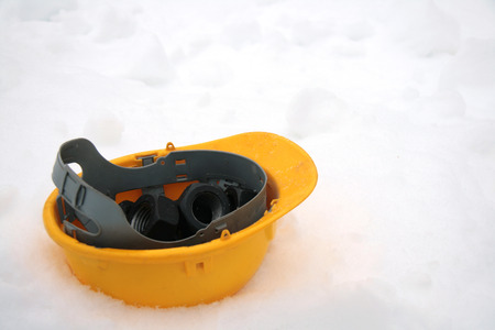Yellow building helmet on snow as container for nutsの写真素材