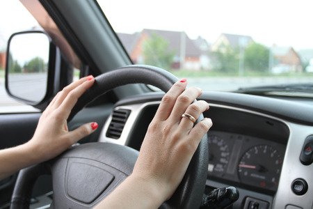 Female hands with manicure on a car wheelの写真素材