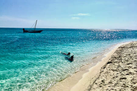 Silhouettes of two indigenous children bathing on the beach in Zanzibarの写真素材