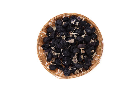 Dried black wolfberry in bamboo basket isolated on whiteの写真素材