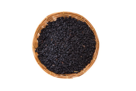 Dried basil seeds in a bamboo basket isolated on whiteの写真素材