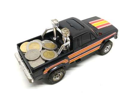 Old dirt toy pickup car/truck carrying coins isolated on white background. Money tranfer conceptの写真素材