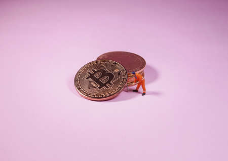 Technician worker figure standing in front of bitcoin. Bitcoin mining concept.の写真素材