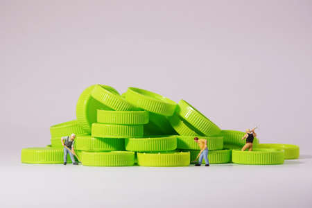 Worker figure standing on plastic cap. Recycle material concept.