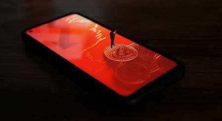 Business man figure standing on a smartphone with a picture of bitcoins.の写真素材