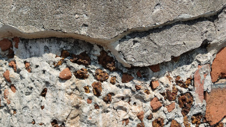 Close-up of textured wall with cracks and stones, ideal for construction or design.