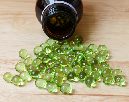 Supplement food,Vitamin E capsule on wooden table.の写真素材