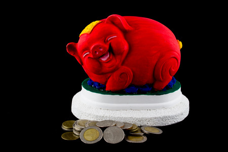 Red piggy bank surrounded by coins on black backgroundの写真素材