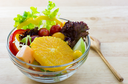 Fresh fruit and Vegetable salad on a wooden plateの写真素材