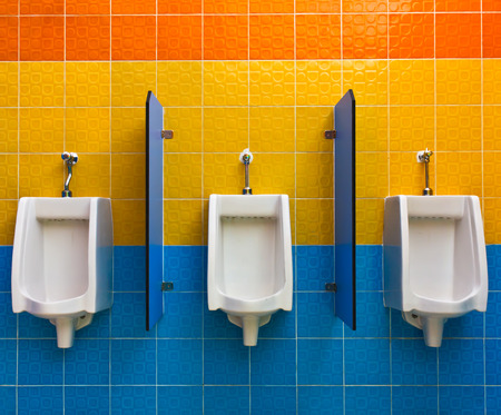 Urinals on colorful wall in public toiletの写真素材