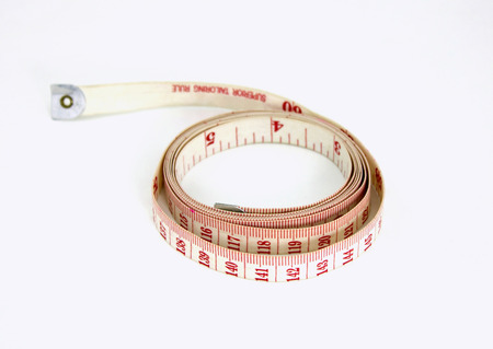 measuring tape laying in a curly circle shape on a white background