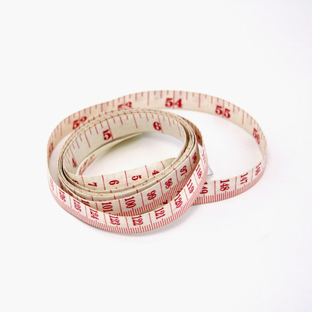 measuring tape laying in a curly circle shape on a white background