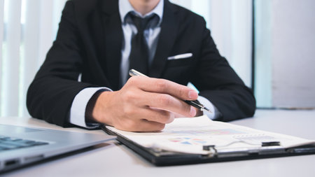 Close-up a business hand signing documents for approval, agreement with partners, working on laptop...