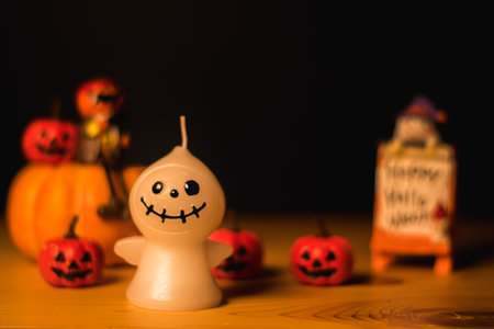 Halloween pumpkins with painted faces and ghost dolls on old wood desk, black background and copy space for textの写真素材