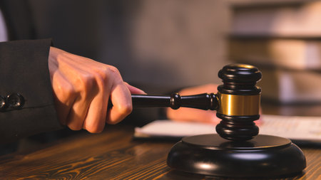 A person holding a judge's hammer, a lawyer reading the law and preparing documents in the office, legal and litigation consulting services.の写真素材
