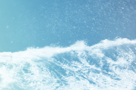 Ocean wave and water splashing on blue sky background with copy space for text.