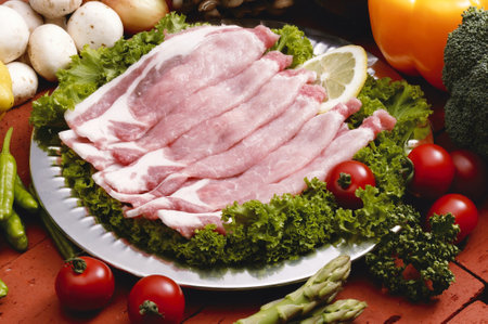 Raw bacon with vegetables on a plate. Shallow dof.の写真素材