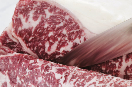 Cutting meat with a knife on a white background, close-upの写真素材