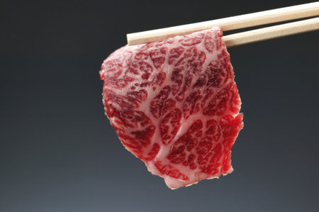 Japanese wagyu beef on chopsticks, isolated on black backgroundの写真素材