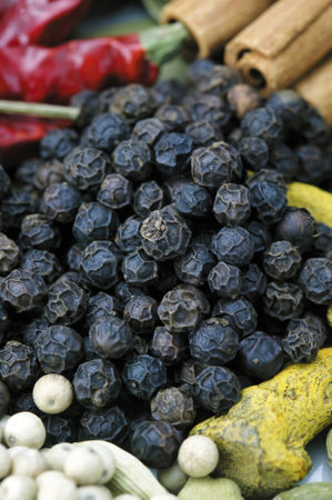 Close up of black pepper and spices on display at a market.