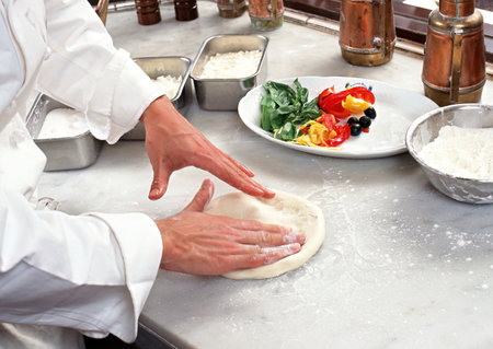 chef making pizza in restaurant kitchen, closeup of hands and ingredientsの写真素材