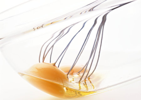 Olive oil in a bowl and a whisk on a white backgroundの写真素材