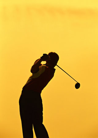 silhouette of a golfer on the golf course at sunsetの写真素材