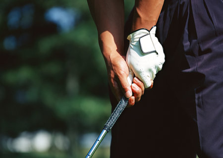 Golfer holding a golf club on the golf course. Close-up.の写真素材