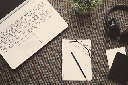 Flat lay. Top view of an office with laptop, notebook, pencil, headphones, glasses, passport, books and plantの写真素材