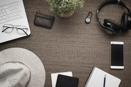 Flatlay. Top view of workspace. Travel or trip planning. Laptop mobile phone, wallet, headphones, women hat, notebook, pencilの写真素材