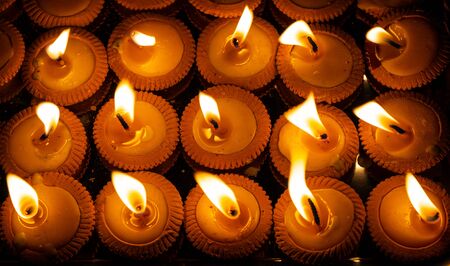 Close up shot of Thai styled candles called Pangpratis or Pangpratheep made from clay, wax and cotton were lit and are burning during Loy Krathong or Yeepeng festival in Chiang Mai, Thailandの写真素材