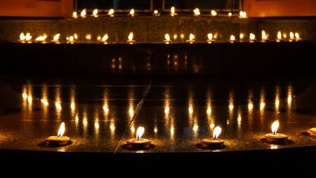 Thai styled candles called Pangpratis or Pangpratheep and made from clay, wax and cotton are placed on the ground around the building and they are lighting and burning during Loy Krathong or Yeepeng festival in Chiang Mai, Thailandの写真素材