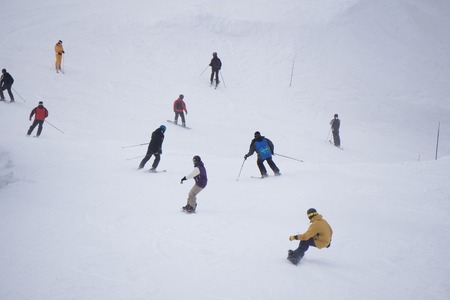 Skiers and snowboarders going down the slope at ski resort.