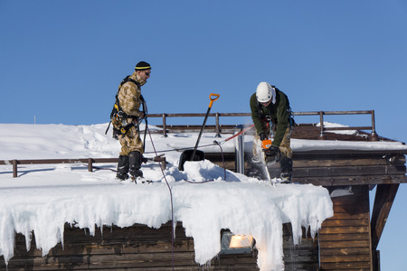 SOCHI, RUSSIA - JANUARY 22, 2015: Industrial climbers take off the snow and icicles from the roofのeditorial素材