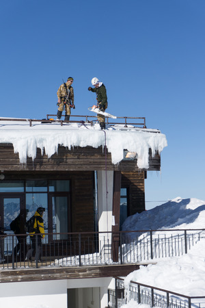 SOCHI, RUSSIA - JANUARY 22, 2015: Industrial climbers take off the snow and icicles from the roofのeditorial素材