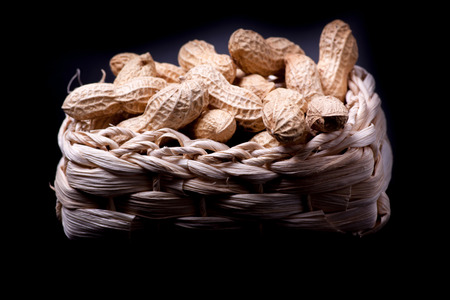 unshelled peanuts peanuts isolated in basket on black backgroundの写真素材