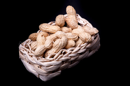 unshelled peanuts peanuts isolated in basket on black backgroundの写真素材