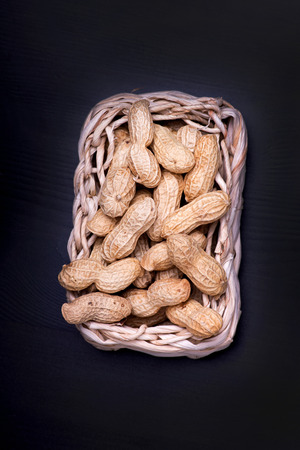 unshelled peanuts peanuts isolated in basket on black backgroundの写真素材