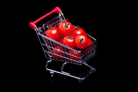 shopping cart with cherry tomatoes, isolated on black backgroundの写真素材